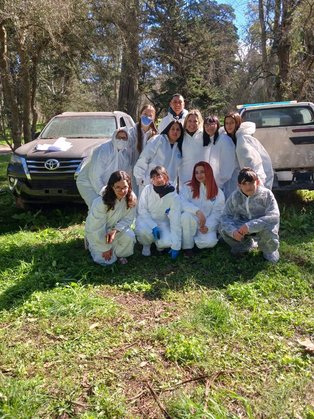 Grupo de alumnos con trajes de protección blancos durante una práctica al aire libre