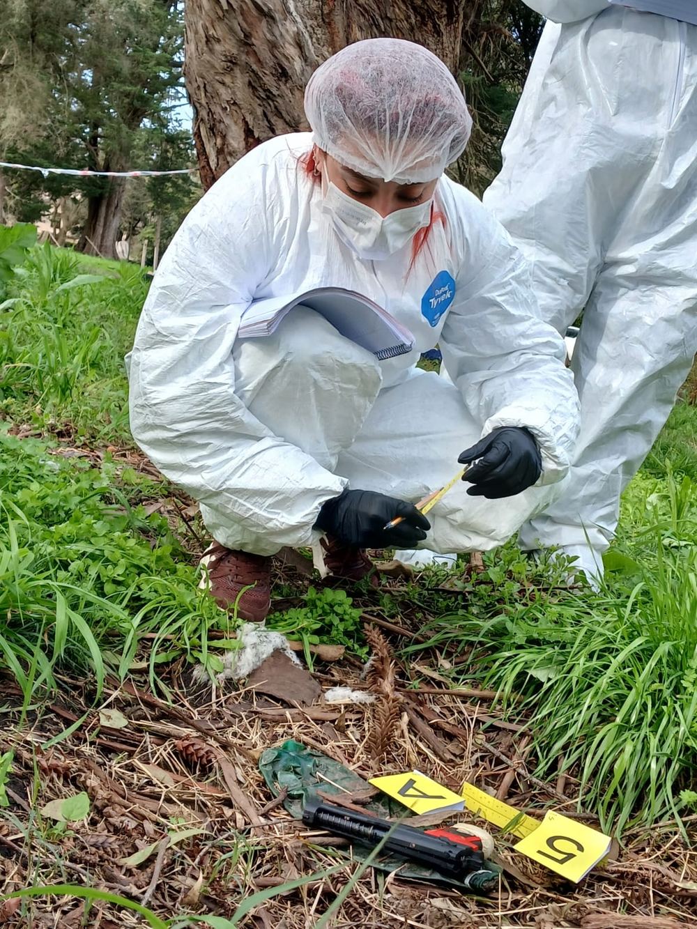 Alumna midiendo un indicio señalizado con marcadores amarillos