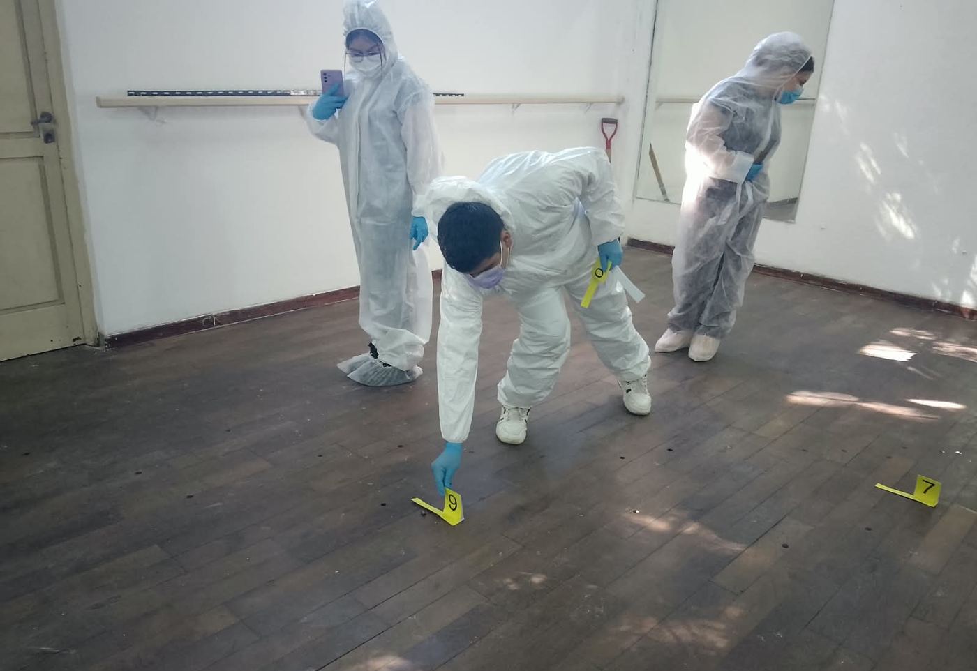 Alumno colocando un marcador numerado sobre el piso en una práctica en interiores