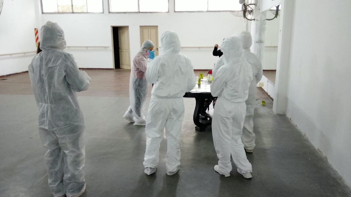 Alumnos con trajes de protección trabajando alrededor de una mesa con indicios